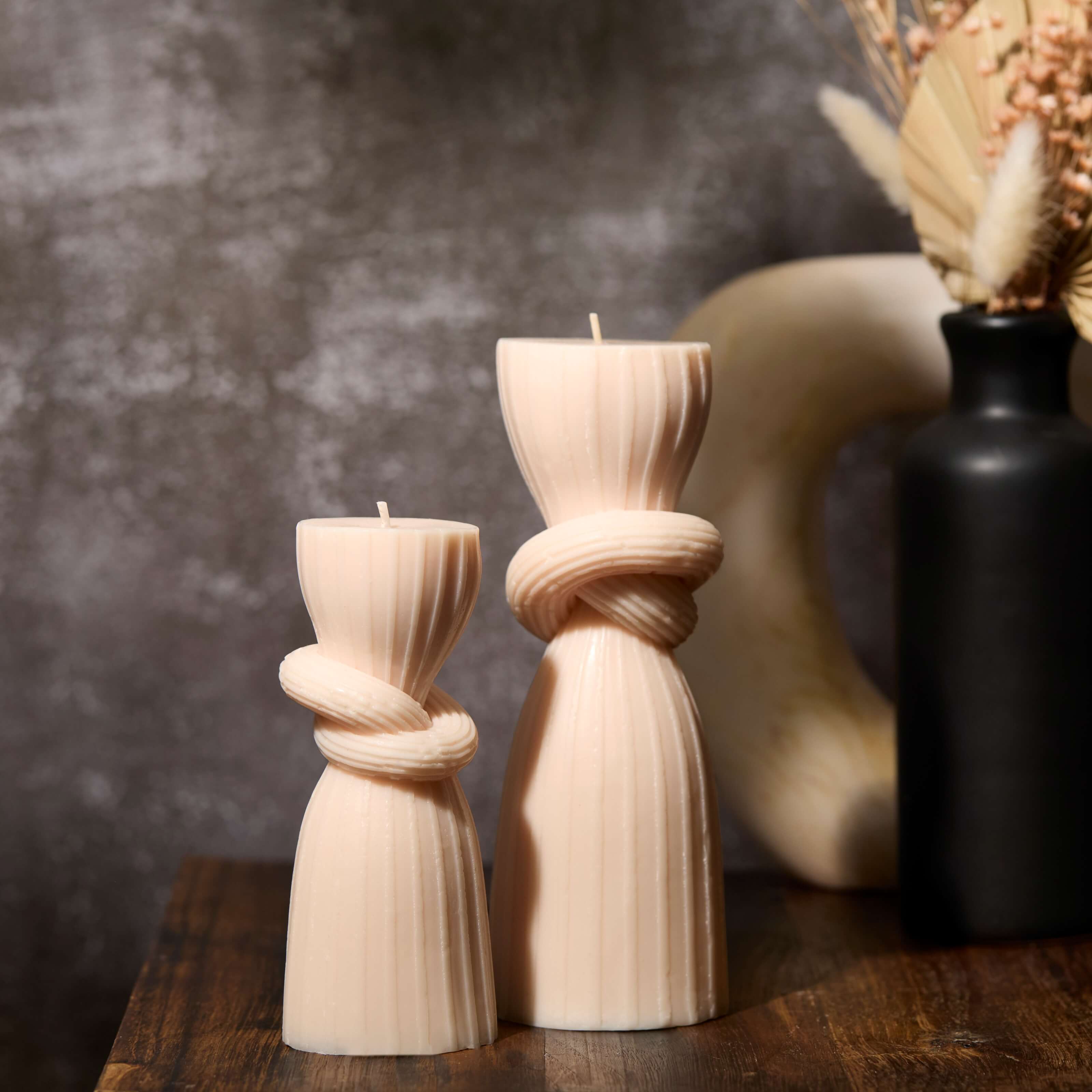 2 pillar candles sitting next to a vase