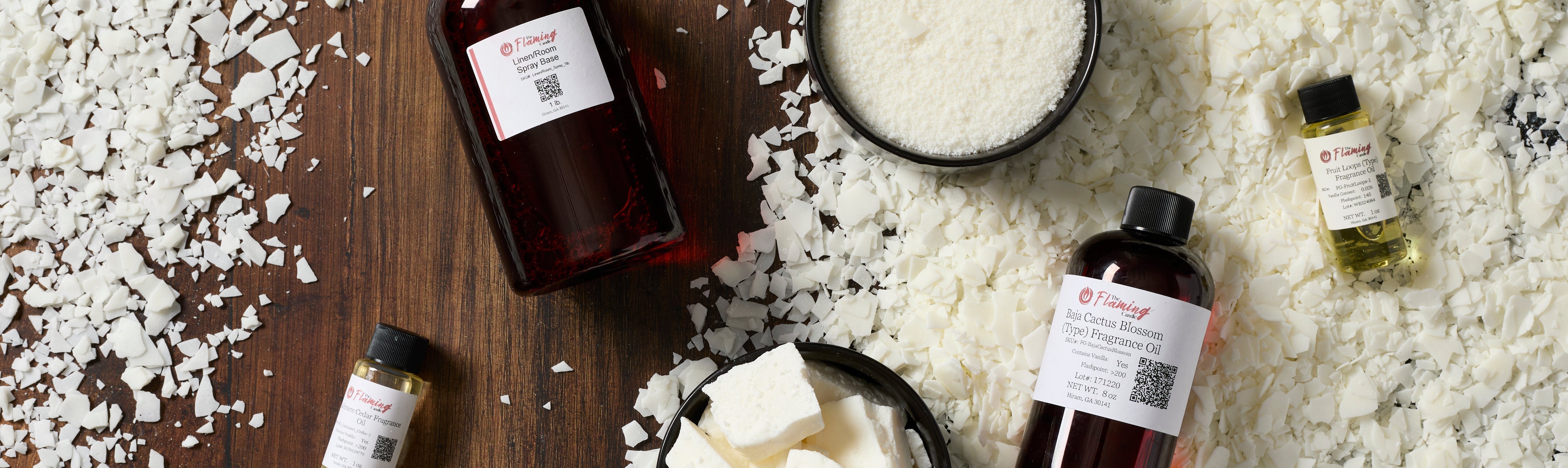 Home fragrance setup featuring The Flaming Candle “Lemon Blossom” fragrance oil, a sleek silver spray bottle, and a clear glass reed diffuser with black reeds on a marble surface against a soft beige background.