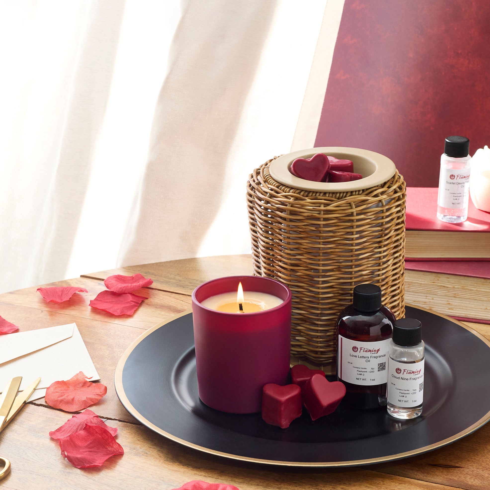 Alt text: Cozy holiday setup featuring The Flaming Candle fragrance oils labeled “Crimson Plumwood,” “Twilight Pine,” and “Ember Grove,” surrounded by pinecones, candles, books, and a green tree-shaped candle.