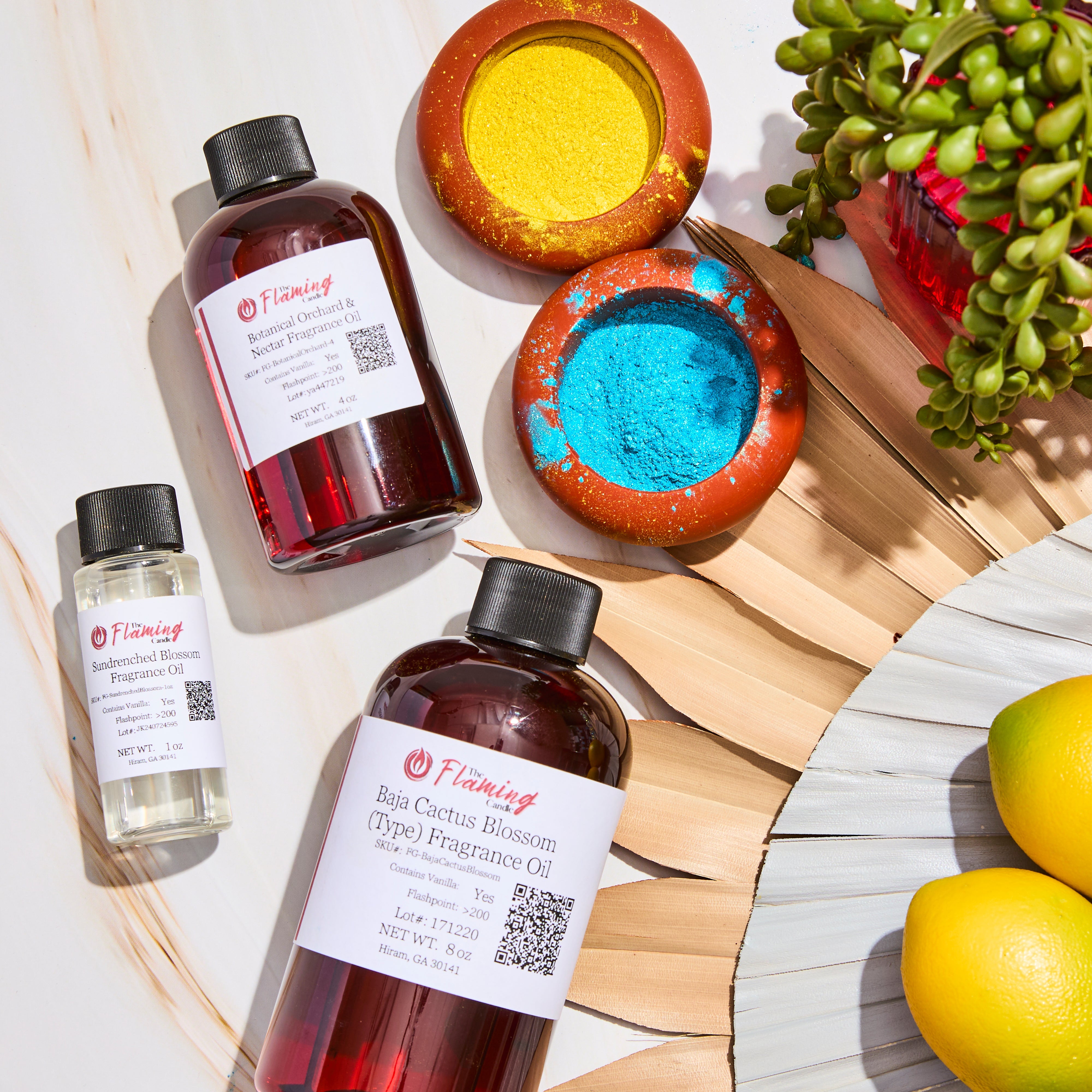 Alt text: Cozy holiday setup featuring The Flaming Candle fragrance oils labeled “Crimson Plumwood,” “Twilight Pine,” and “Ember Grove,” surrounded by pinecones, candles, books, and a green tree-shaped candle.