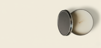 Top view of an open 16 oz metal candle tin filled with white wax and a centered wick, with the lid beside it on a light background.
