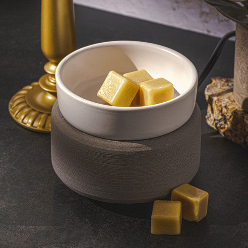 White bowl with brown base containing yellow cubes on a dark surface