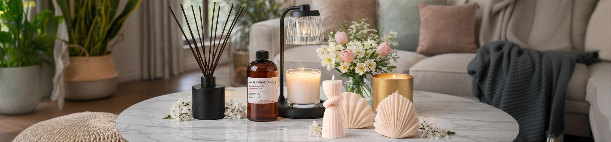 Marble coffee table with lit candles, reed diffuser, amber fragrance oil bottle, and pastel decorative pieces, set in a cozy living room with sofa, pillows, throw blanket, and potted plant in soft natural light.