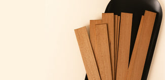 A bundle of natural wooden candle wicks arranged on a sleek black tray, highlighting their smooth texture and warm, handcrafted look.